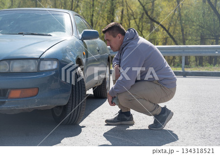 A Caucasian man tries to repair damage to a car body with his hands. A Caucasian man tries to repair damage to a car body with his hands. 134318521