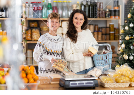 Adolescence boy with mother choose consider snacks in shop on eve of New Year 134320763