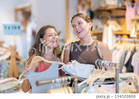 Two women standing in a boutique and choosing clothes Two women standing in a boutique and choosing clothes 134320808