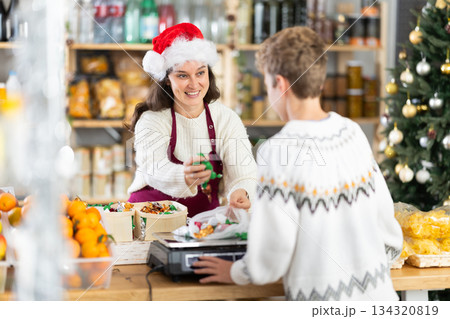 Female seller weighs candies for boy buyer Female seller weighs candies for boy buyer 134320819