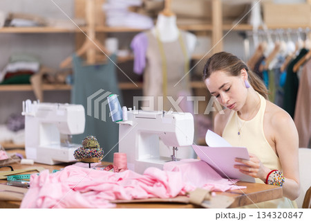 Upset female dressmaker checking some documents in tailor shop 134320847