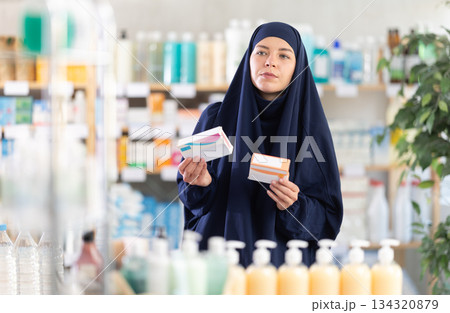 Young woman in hijab chooses pills 134320879