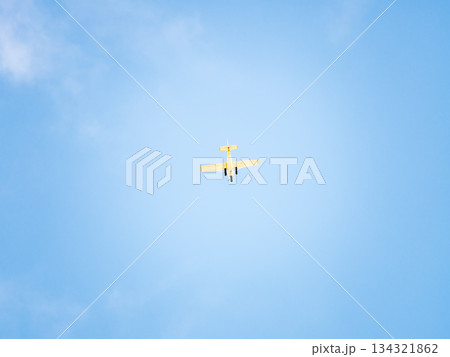 Small ultralight airplane with overhead wing and single propeller flying in sunset sky. 134321862