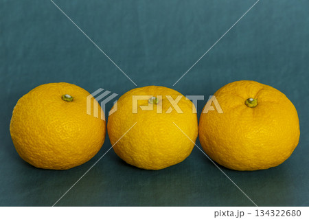 濃い青緑色の背景に横一列に並べられた柚子三つ 冬至や和風、柑橘系の素材のイメージ 濃い青緑色の背景に横一列に並べられた柚子三つ 冬至や和風、柑橘系の素材のイメージ 134322680
