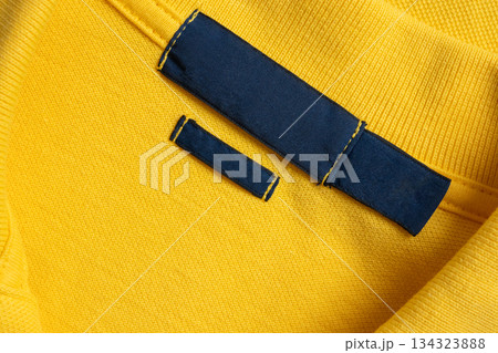 Blank blue laundry care clothes label on yellow shirt fabric texture background 134323888