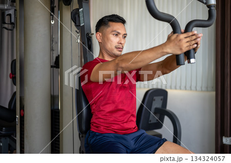Fitness coach trainer middle aged man sitting and using exercise equipment while working out in gym. Fitness coach trainer middle aged man sitting and using exercise equipment while working out in gym. 134324057