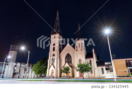 St. Mary's Catholic Church stands in downtown Lincoln, Nebraska, USA. Gothic Revival architecture features twin spires and a modern bell tower illuminated at night 134325445