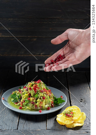 Salad with vegetables and avocado. Salad sprinkled with pomegranate berries. Pomegranate on the hand. Salad with vegetables and avocado. Salad sprinkled with pomegranate berries. Pomegranate on the hand. 134325664