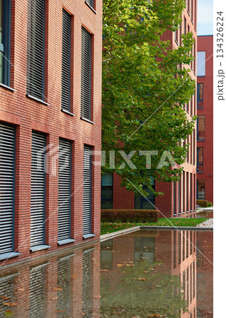 Modern brick building facade with window blinds and water reflection Modern brick building facade with window blinds and water reflection 134326224