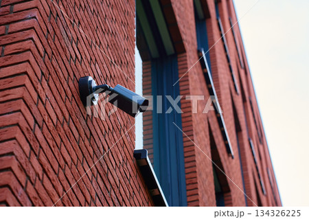 Surveillance camera mounted on a red brick wall exterior Surveillance camera mounted on a red brick wall exterior 134326225