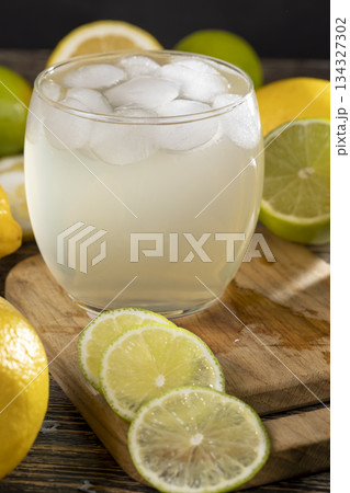 cold lemon drink with the addition of pieces of pure ice in a glass, sweet drink with lemon flavor and whole juicy lemons and limes cold lemon drink with the addition of pieces of pure ice in a glass, sweet drink with lemon flavor and whole juicy lemons and limes 134327302