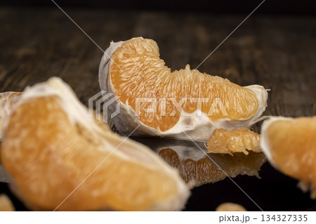 half of an orange citrus on a black mirror surface, ripe and sweet and juicy citrus is reflected on the black mirror, closeup 134327335