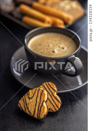 Heart shaped cookie and coffee cup on black table. 134328154