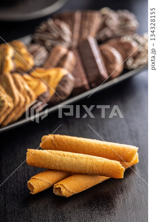 Sweet wafer rolls on black table. 134328155