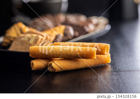 Sweet wafer rolls on black table. 134328156