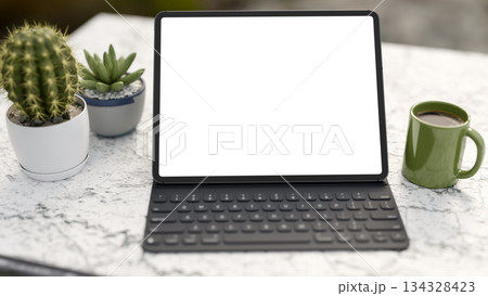 White screen tablet with keyboard and mug cup aside cactus on marble table in a living room or cafe. 134328423
