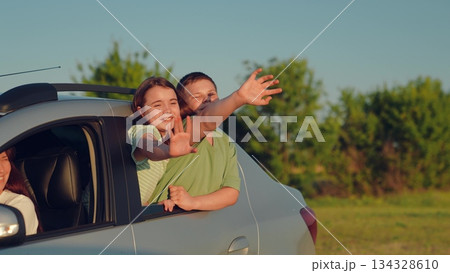 Woman mother child driving car, kid boy girl waving their hands out car window, happy family cheerful people childhood, country breeze blowing through car while children wave happily outside, playful 134328610