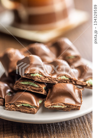 Chocolate bar with pistachios cream on plate on wooden table. 134329589