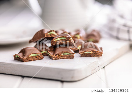 Chocolate bar with pistachios cream on white table. Chocolate bar with pistachios cream on white table. 134329591