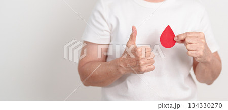 Elderly woman with red Blood drop paper for concept of June World Blood Donor day, Donation, January Blood donor awareness month, April Hemophilia awareness day, May Thalassemia Day, Anemia awareness Elderly woman with red Blood drop paper for concept of June World Blood Donor day, Donation, January Blood donor awareness month, April Hemophilia awareness day, May Thalassemia Day, Anemia awareness 134330270