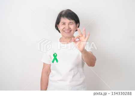 Elderly with Green Ribbon for concept of July Eye Injury Prevention month, January Glaucoma Awareness month, February Gallbladder and Bile duct and October Liver cancer. Health and world cancer day Elderly with Green Ribbon for concept of July Eye Injury Prevention month, January Glaucoma Awareness month, February Gallbladder and Bile duct and October Liver cancer. Health and world cancer day 134330288