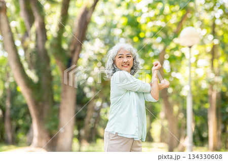 Old age asian woman grandmother crossing both arms stretching while warming up or exercising in park 134330608