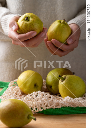 Fresh pear in mesh bag holding by woman hand Fresh pear in mesh bag holding by woman hand 134330720