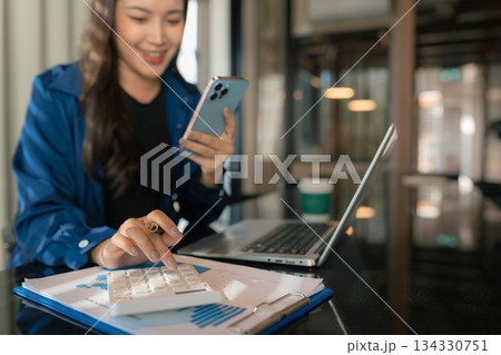 Business woman calculates financials with graph paper on the table on the cost. Business woman calculates financials with graph paper on the table on the cost. 134330751