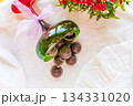 Chocolates are poured out of a green glass glass onto a white cloth with festive decor in the background.  134331020