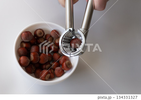 In a white plate hazelnut kernels in the shell, on top of the nutcracker in his hands 134331327