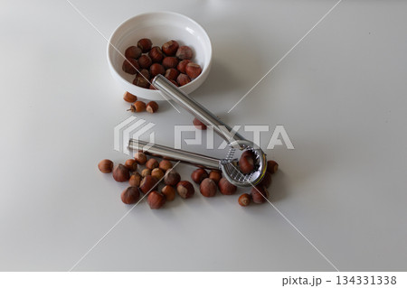 The nutcracker lies on the nuts, next to the plate with hazelnuts 134331338