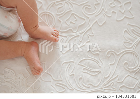 Baby feet on a soft embroidered blanket in a cozy room Baby feet on a soft embroidered blanket in a cozy room 134331683
