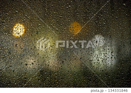 Rainy Glass Night With Bokeh Lights and Droplets Creating Moody Urban Scene Through Street View 134331846