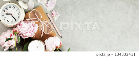 Feminine Workspace with Clock, Flowers, and Stationery 134332411