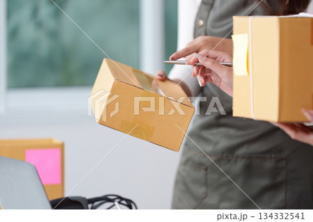 E-commerce collaboration. Women handling packages and managing orders on a laptop. 134332541