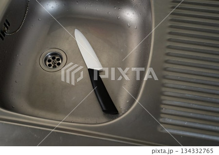Ceramic knife lying in metal sink Ceramic knife lying in metal sink 134332765