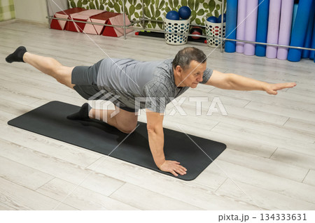 Senior caucasian man performing bird dog core exercise on fitness mat at home. Balance training, stability and healthy aging concept. 134333631