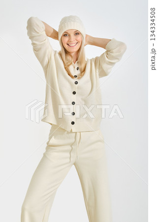 Smiling woman in cream outfit with hat posing against white background Smiling woman in cream outfit with hat posing against white background 134334508
