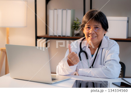 Portrait senior asian doctor woman working on laptop computer on desk in clinic. 134334560