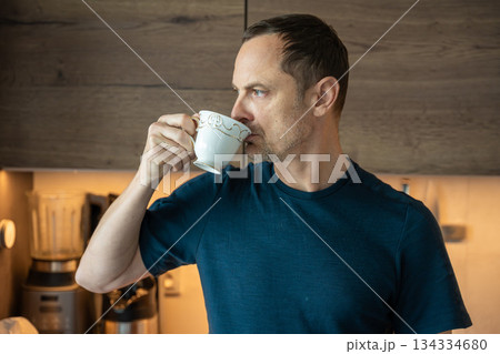 Man drinking coffee in a modern kitchen. Morning beverage ritual. 134334680