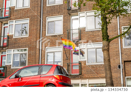 LGBT flag is fluttering on wall facade. Netherlands Amsterdam modern building architecture houses. LGBT flag is fluttering on wall facade. Netherlands Amsterdam modern building architecture houses. 134334730