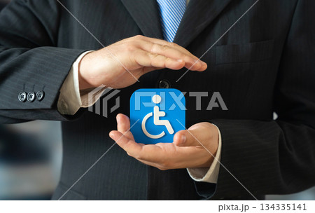 A businessman holds a symbol for people with disabilities. Support for people with limited mobility. A bar-free environment in the city. Inclusion policies improve accessibility A businessman holds a symbol for people with disabilities. Support for people with limited mobility. A bar-free environment in the city. Inclusion policies improve accessibility 134335141