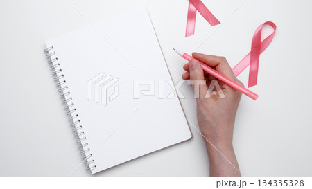 Symbolizing breast cancer awareness. Woman scheduling preventive checkup with visible pink ribbon 134335328