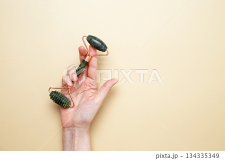 Female hands holding marble face roller tools for skincare routine 134335349
