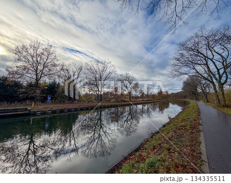 Wide Canal Path Under Striking Clouds Suitable For Cycling And Peaceful Recreation Activities 134335511