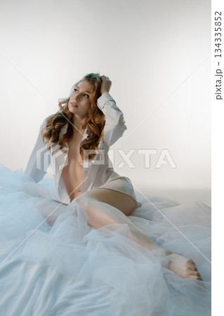 Sensual woman in lingerie relaxes gracefully on soft fabric backdrop 134335852