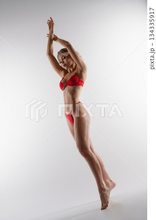 Woman dancing gracefully in a lingerie studio setting with soft lighting 134335917