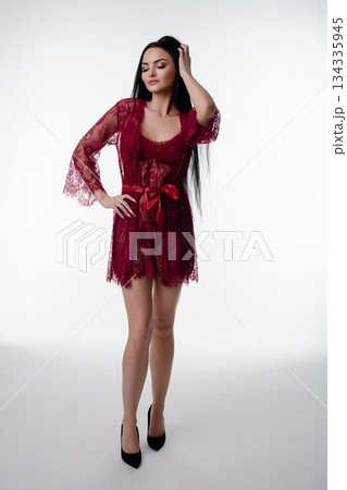 Elegant woman in lace lingerie poses confidently in a studio setting 134335945