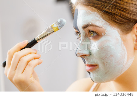 Girl black mask on half face apply white mud Girl black mask on half face apply white mud 134336449