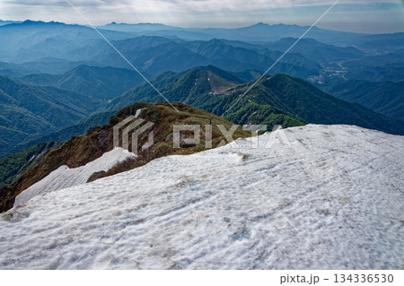 谷川岳山頂直下の雪渓から天神平・上州武尊山・赤城山の山並み 134336530